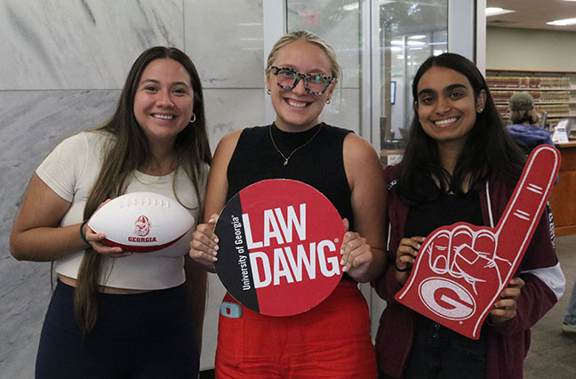 three students holding UGA promotional items
