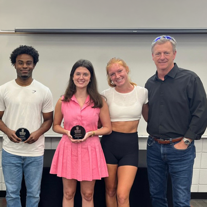 Michael Cheney stands with sports management students holding awards