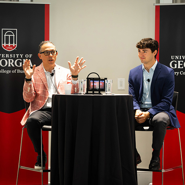 Alumnus NIck Donkar sits at a table with a student and delivers International Business presentation in Stelling Study. 