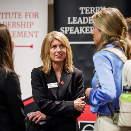 Stacy Campbell talks to students in front of ILA and Terry Leadership Speaker Series banners. 