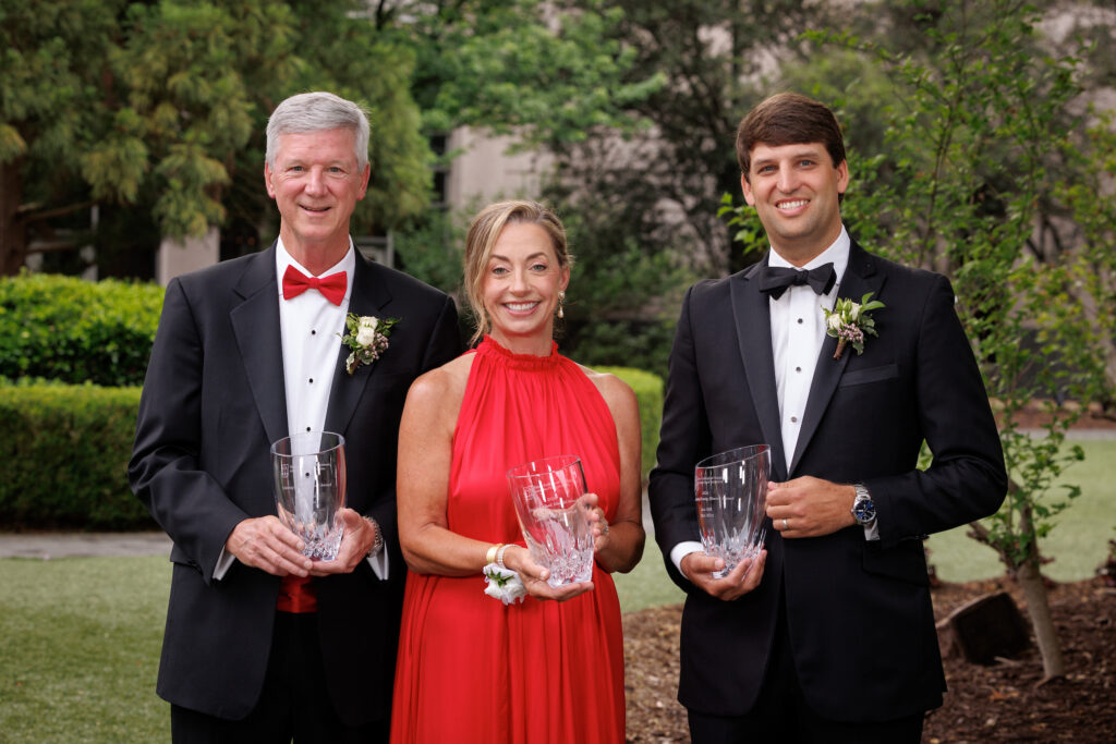 Terry alumni Scott Sink, Linda Brightwell and Alex Hill pose with their alumni award trophies wearing formal wear.