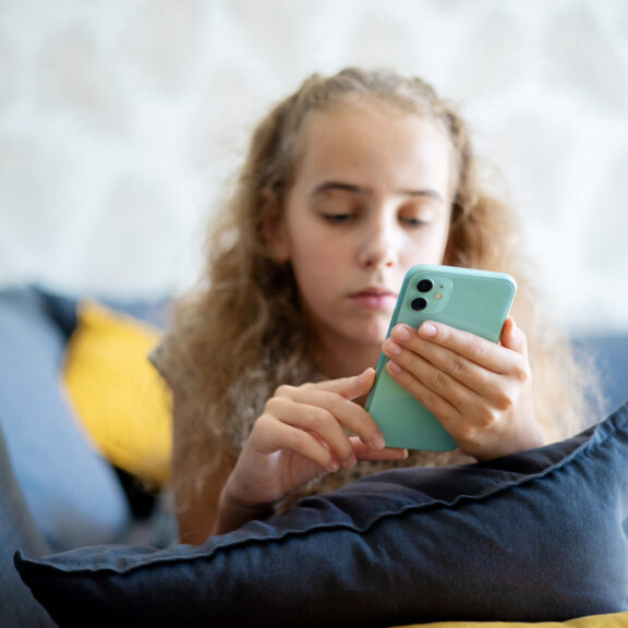 Photo illustration of a little girl looking at a smart phone 