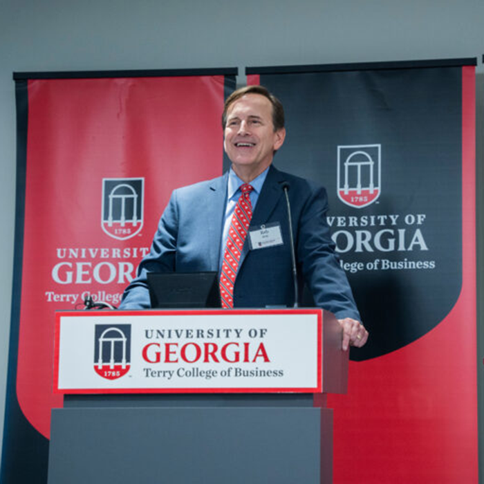 Rob Hoyt stands behind a Terry College podium in front of red and black UGA-branded banners
