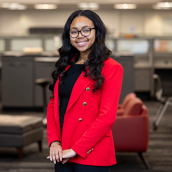 Jhaycee Barnes stands in front of office cubicles wearing a Georgia red blazer.