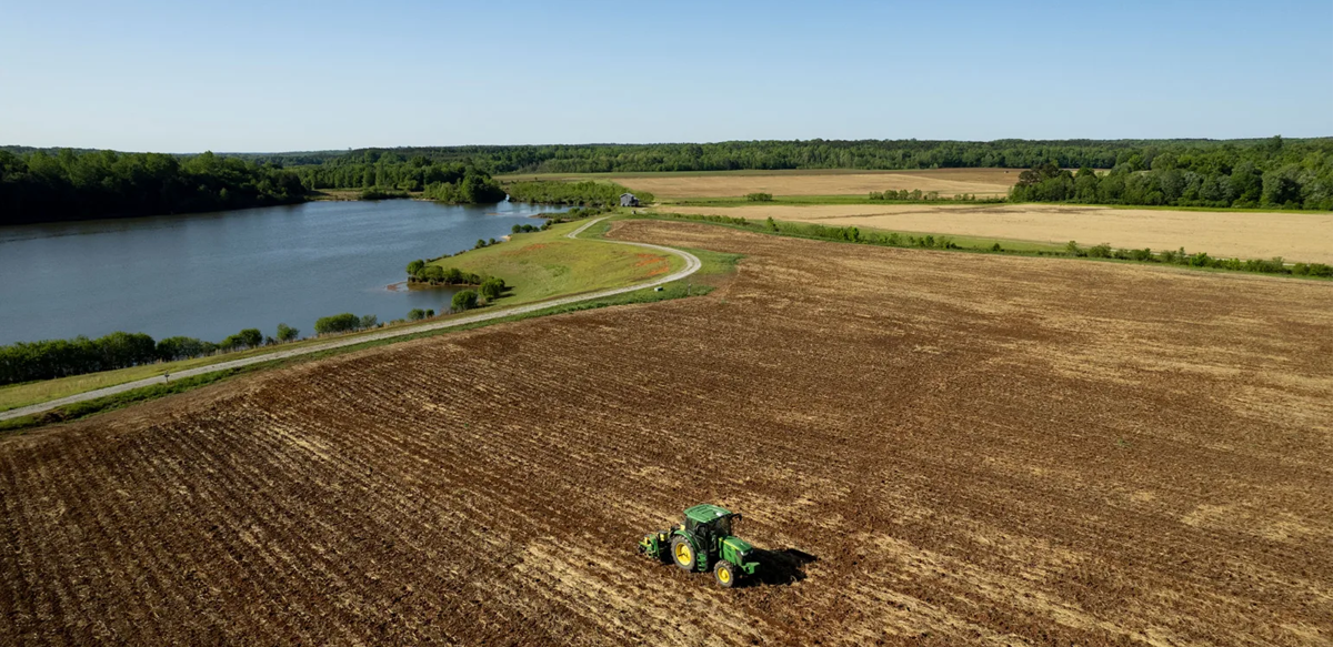 An aerial view of a tractor plowing a field with a lake in the background (Photo by Andrew Davis Tucker/UGA)